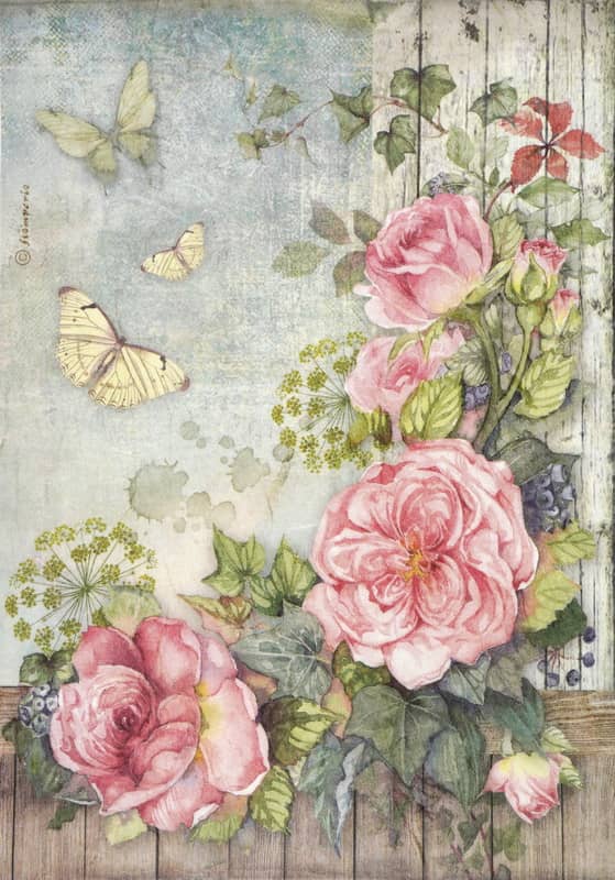 Vintage-inspired decoupage rice paper featuring a large cluster of blooming pink roses with green leaves and ivy vines, positioned on the right side against a weathered wooden fence texture and a distressed light blue background, with three yellow butterflies fluttering on the left.